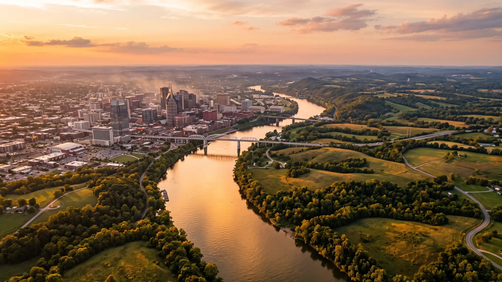 Aerial view of the Cumberland River winding past the Nashville skyline and Middle Tennessee farmland at sunset